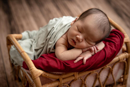 小さなベッドの上でうつ伏せで眠る新生児の記念フォト（撮影：PHOTO104 Toshi）