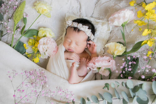 色とりどりの花に囲まれて眠る新生児の女の子のニューボーンフォト（撮影：笹木 祐美）