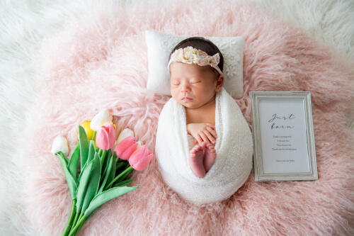 ピンクのカーペットの上でおくるみに包まれて眠る生後一ヶ月の女の子のニューボーンフォト（撮影：青柳理沙）