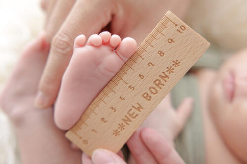 新生児の赤ちゃんの足のサイズを木製の定規で測っている様子を撮影した写真（撮影：小倉美幸）
