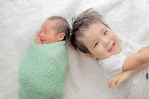 2歳のお兄ちゃんとおくるみに包まれた新生児の赤ちゃんのツーショット写真（撮影：山﨑早江子）
