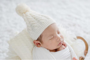白いおくるみを着て白いニット帽を被った赤ちゃん人形